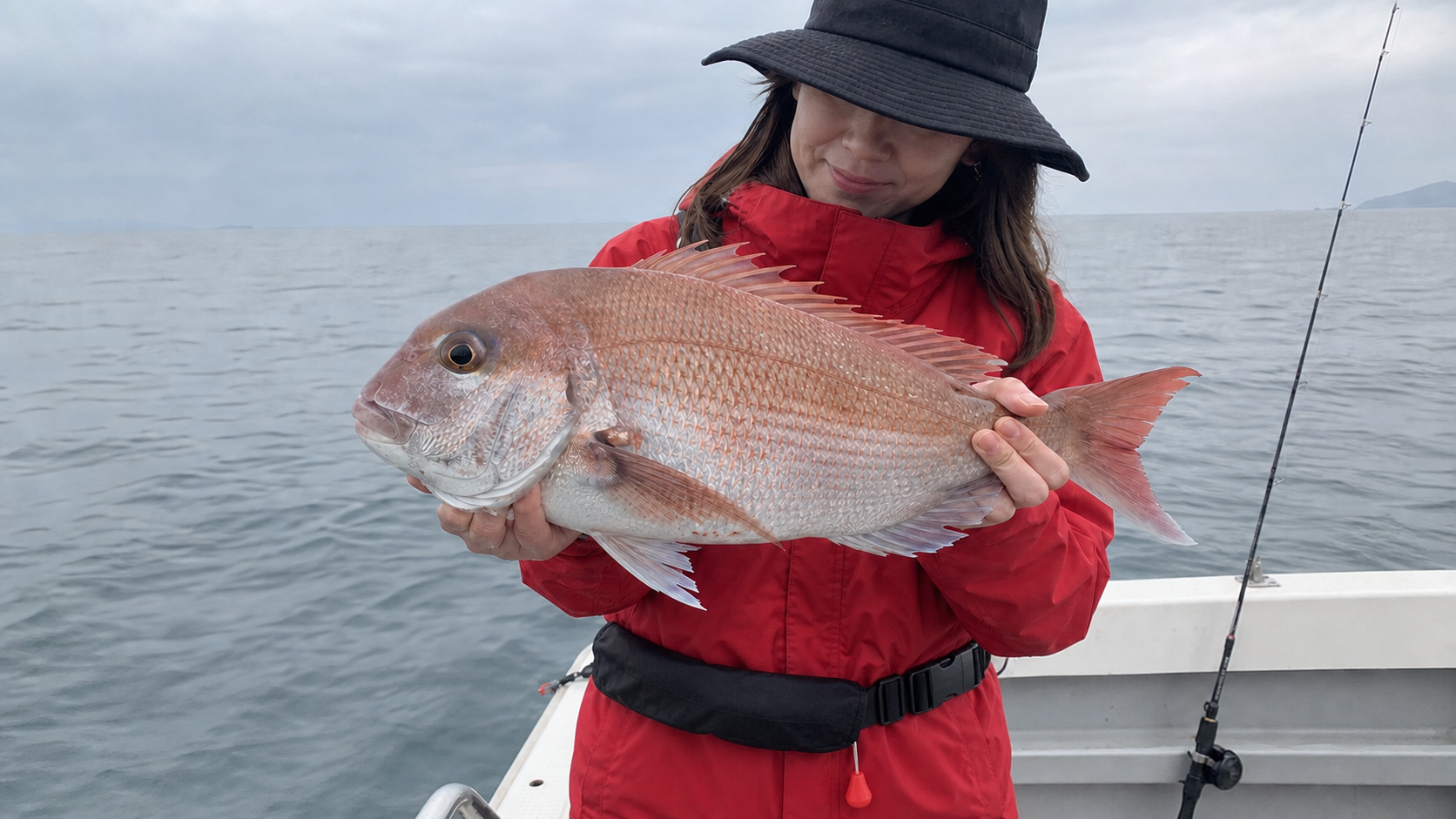 釣り上げた真鯛を両手で持って釣果を見せる女性アングラー