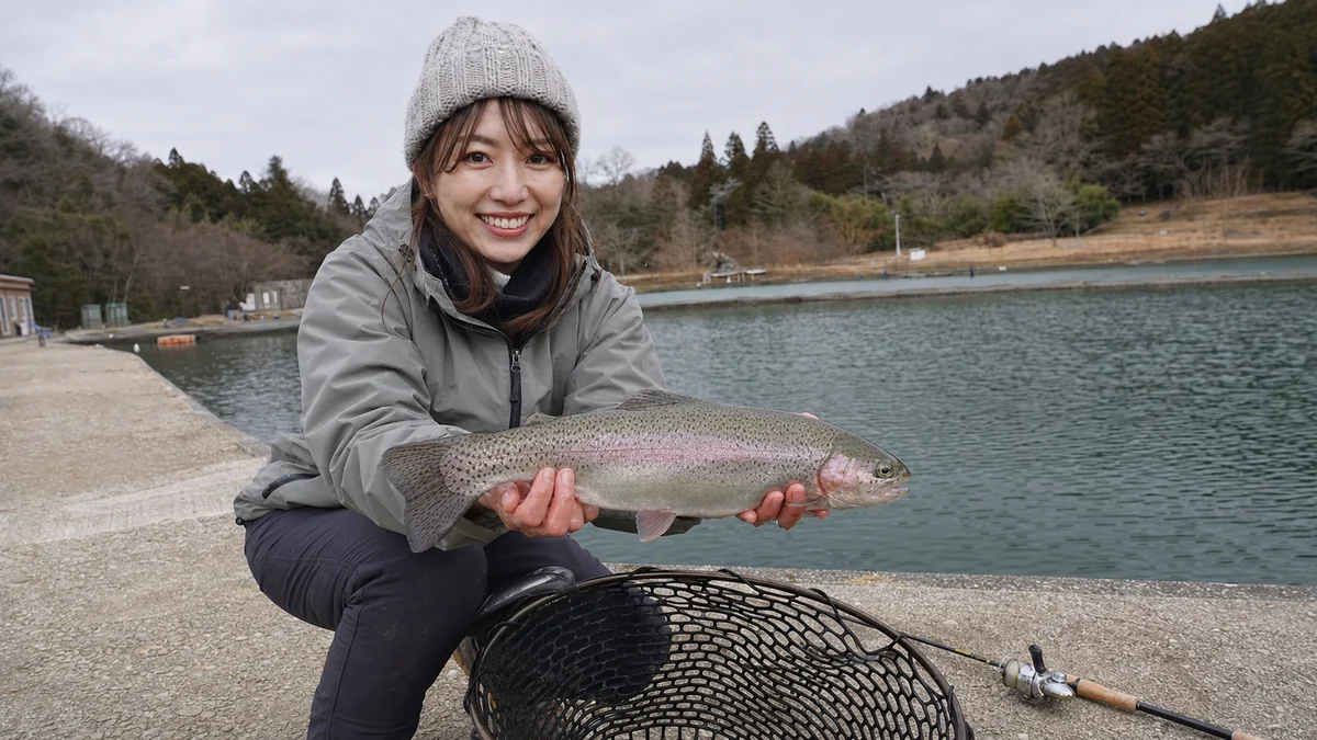 管理釣り場でニジマスの釣果を見せる女性