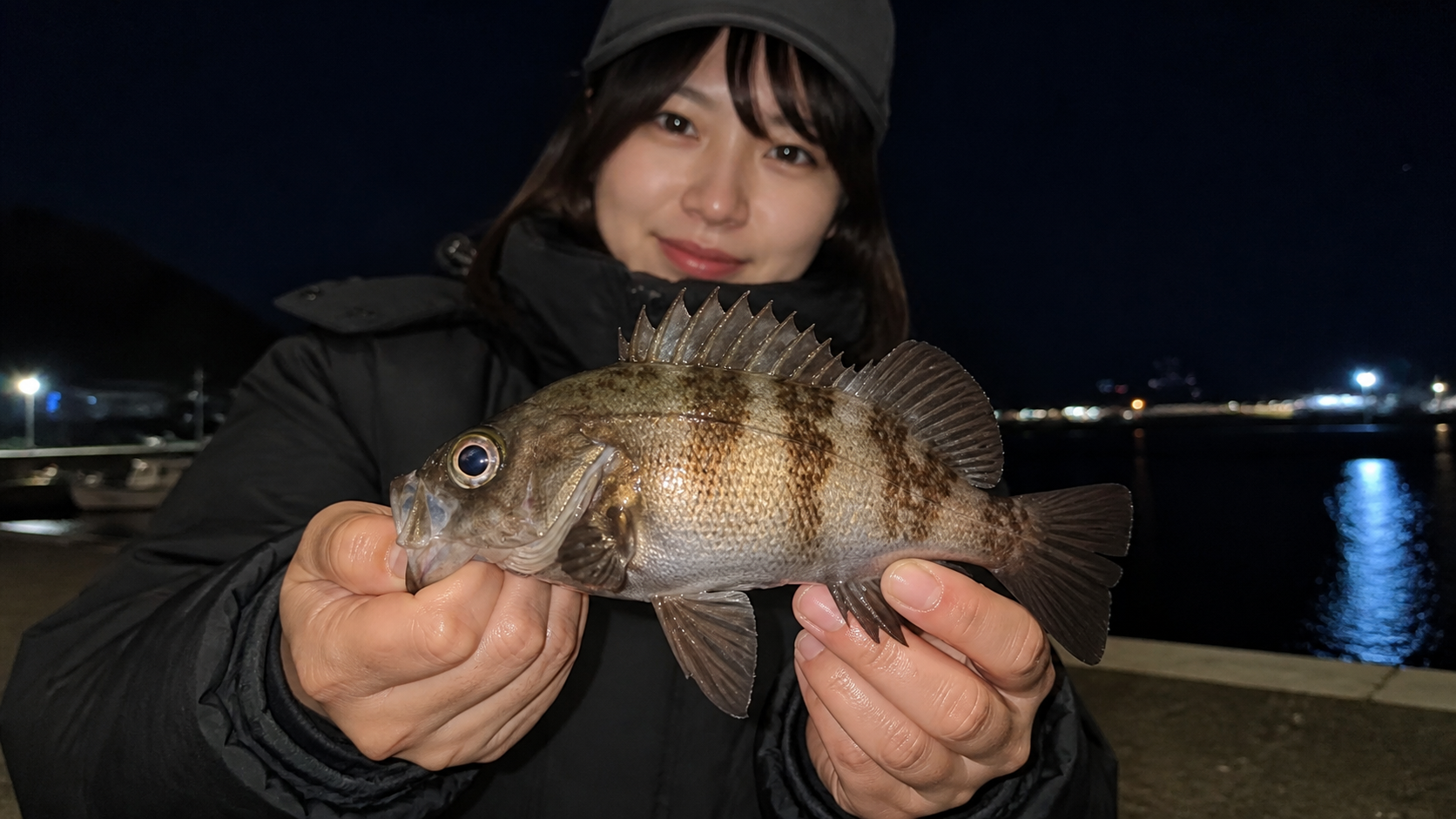 冬の夜にメバルを見せる女性アングラー